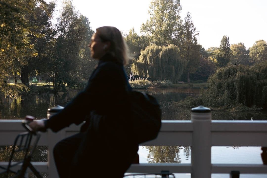 Woman cycling on a bridge by a tranquil lake